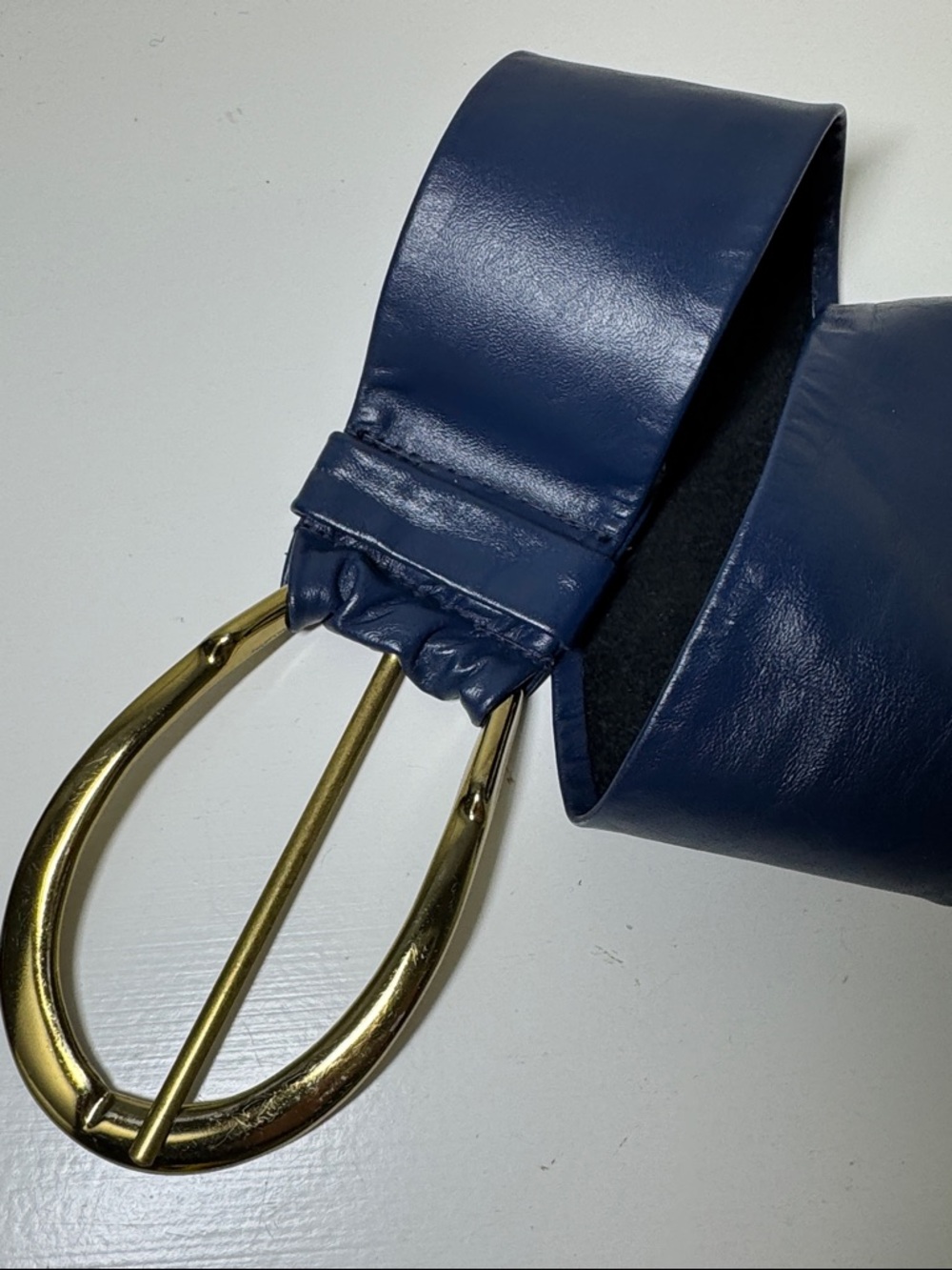 Blue leather belt with gold tone buckle.